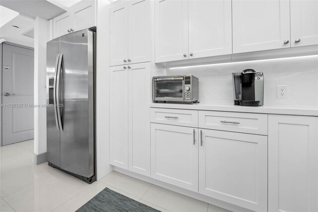 kitchen with stainless steel fridge, white cabinets, and light tile patterned flooring