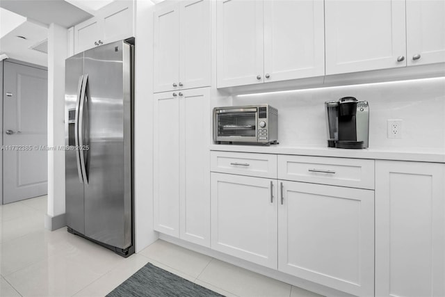 3675 N Country Club Dr Unit 1006, Aventura, FL 33180 - kitchen with stainless steel refrigerator with ice dispenser, light tile patterned flooring, white cabinetry, and light countertops