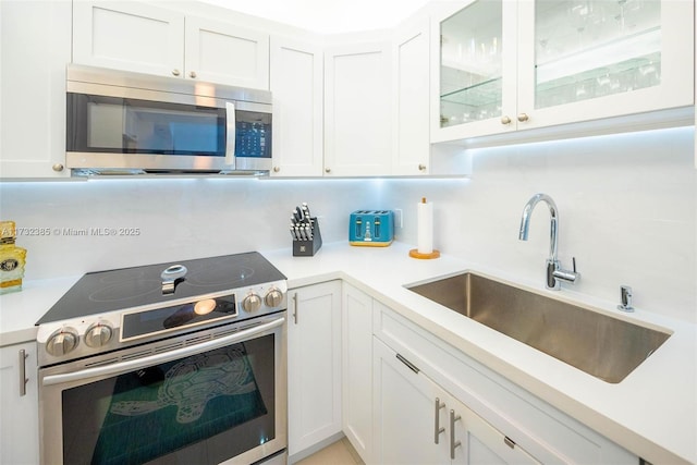 3675 N Country Club Dr Unit 1006, Aventura, FL 33180 - kitchen featuring stainless steel appliances, white cabinetry, light countertops, decorative backsplash, and glass insert cabinets