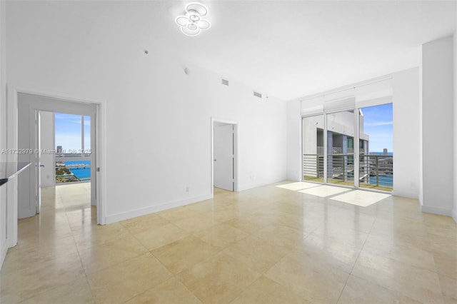 empty room with a wealth of natural light, a high ceiling, and visible vents