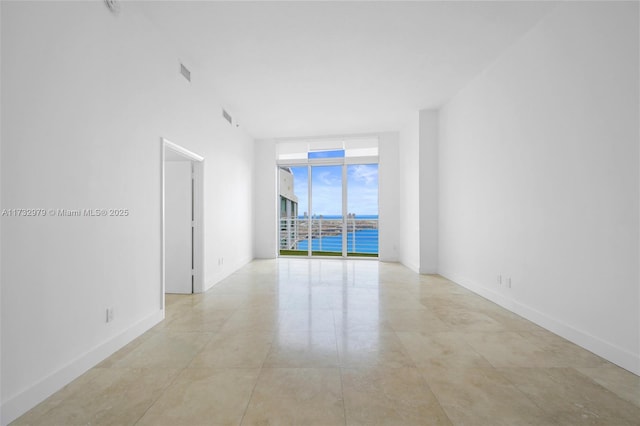 empty room featuring baseboards, visible vents, and floor to ceiling windows