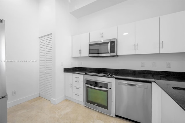 kitchen featuring stainless steel appliances, dark stone countertops, baseboards, and white cabinetry
