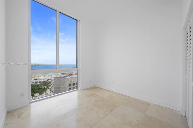 tiled spare room featuring baseboards and a water view