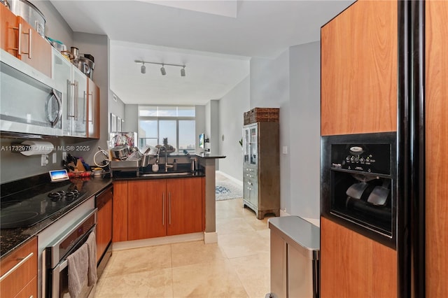 kitchen featuring appliances with stainless steel finishes, rail lighting, sink, light tile patterned floors, and kitchen peninsula