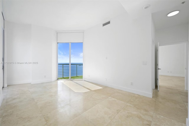 unfurnished room with visible vents, baseboards, floor to ceiling windows, and a water view
