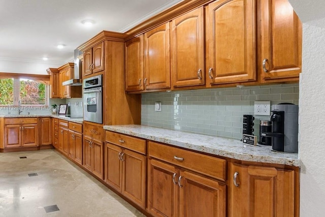 kitchen featuring sink, crown molding, light stone countertops, decorative backsplash, and stainless steel oven