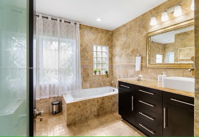 bathroom with a relaxing tiled tub, tile patterned floors, tile walls, and vanity