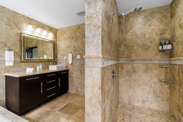 bathroom featuring vanity, a tile shower, and tile walls