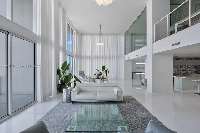 dining space with a towering ceiling, a chandelier, and light tile patterned floors