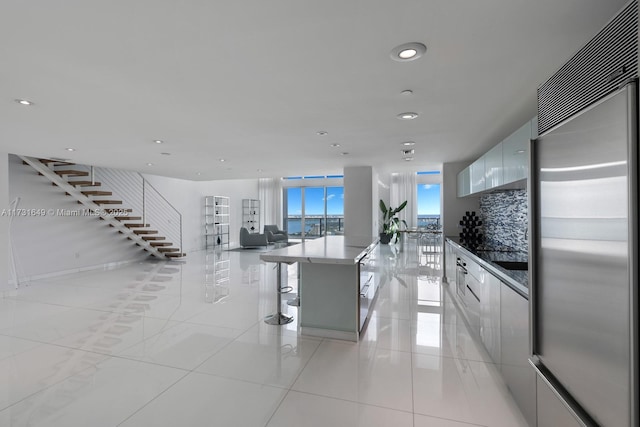 kitchen featuring white cabinetry, a kitchen island, a kitchen breakfast bar, and built in refrigerator