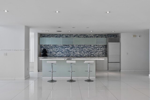 kitchen with a spacious island, white cabinetry, stainless steel oven, light tile patterned floors, and black electric stovetop