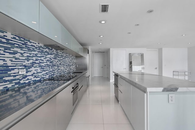 kitchen featuring stainless steel oven, black electric cooktop, a large island, decorative backsplash, and white cabinets