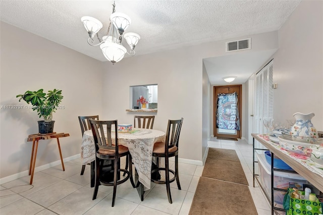 tiled dining room featuring a textured ceiling and a notable chandelier