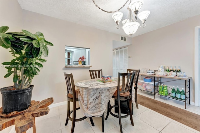 tiled dining space featuring a textured ceiling and a chandelier