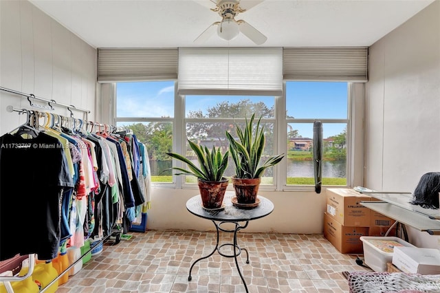 sunroom with a water view and ceiling fan