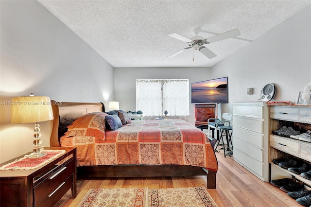 bedroom with a textured ceiling, light hardwood / wood-style flooring, and ceiling fan