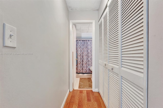 corridor featuring light hardwood / wood-style floors and a textured ceiling