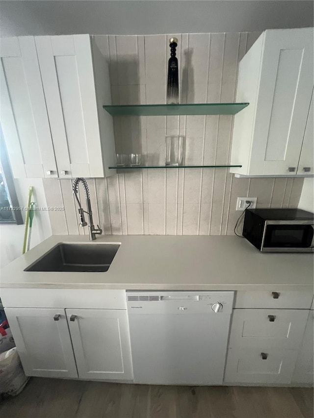 kitchen featuring sink, tasteful backsplash, dishwasher, hardwood / wood-style floors, and white cabinets