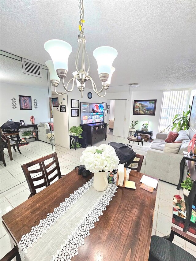 tiled dining space featuring a notable chandelier and a textured ceiling