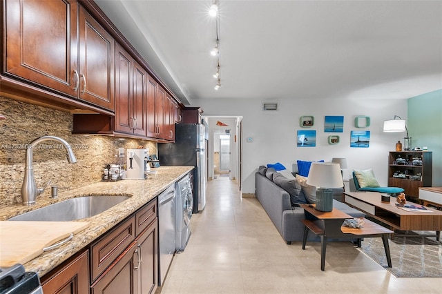 kitchen featuring washer / dryer, sink, light stone counters, stainless steel appliances, and backsplash