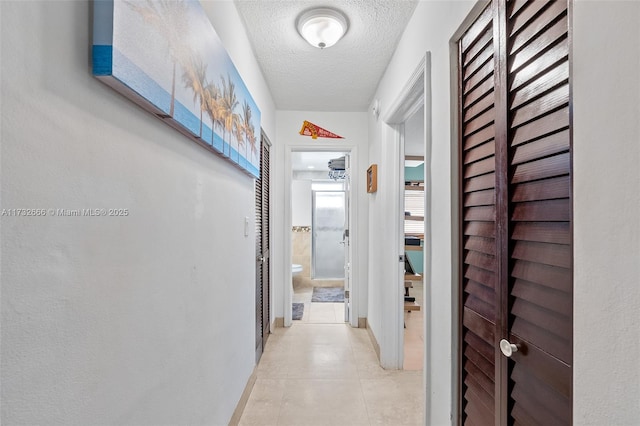 hallway featuring light tile patterned floors and a textured ceiling