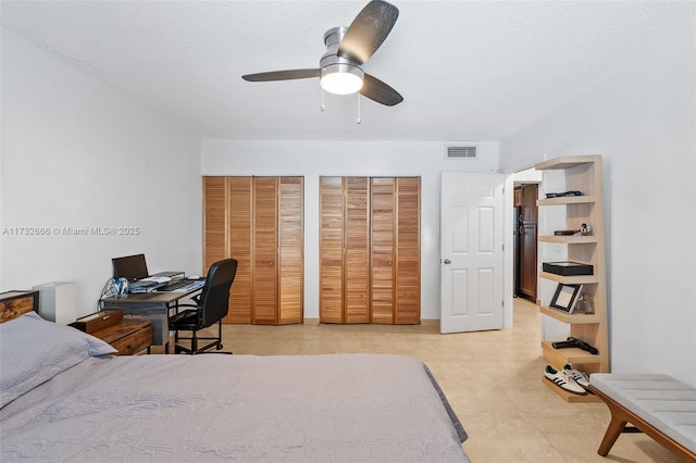 bedroom featuring multiple closets, refrigerator, a textured ceiling, and ceiling fan