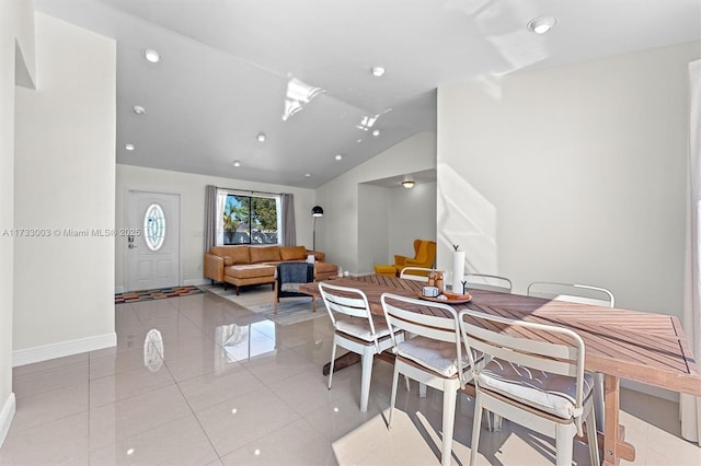 dining space with light tile patterned floors and vaulted ceiling