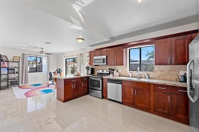 kitchen with sink, decorative backsplash, stainless steel appliances, and light stone countertops