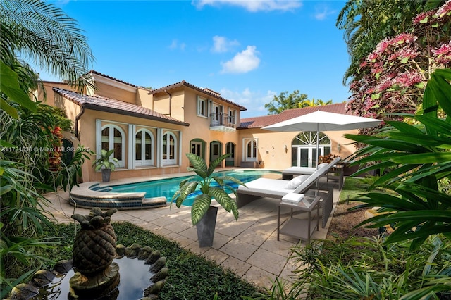 rear view of house featuring an outdoor pool, french doors, a patio, and a balcony