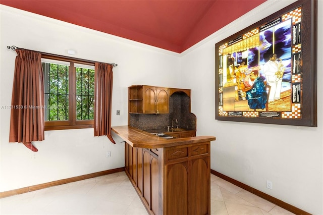 bar featuring vaulted ceiling, tasteful backsplash, light tile patterned flooring, and baseboards