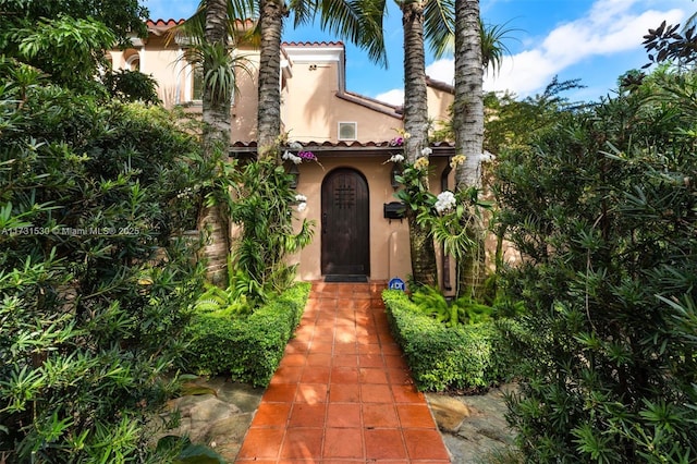 property entrance featuring a tile roof and stucco siding