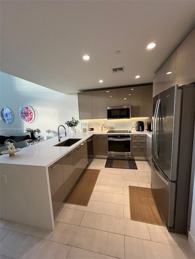 kitchen with sink, light tile patterned floors, gray cabinets, kitchen peninsula, and stainless steel appliances