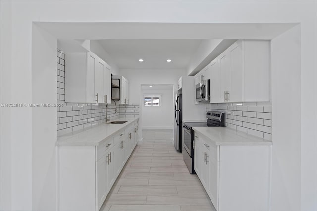 kitchen featuring white cabinetry, sink, light stone counters, and stainless steel appliances