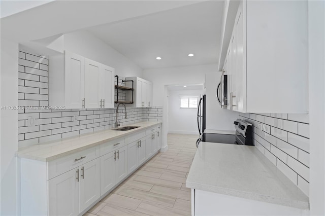 kitchen with sink, backsplash, stainless steel range with electric cooktop, and white cabinets