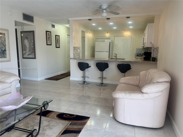 tiled living room featuring sink, a textured ceiling, and ceiling fan