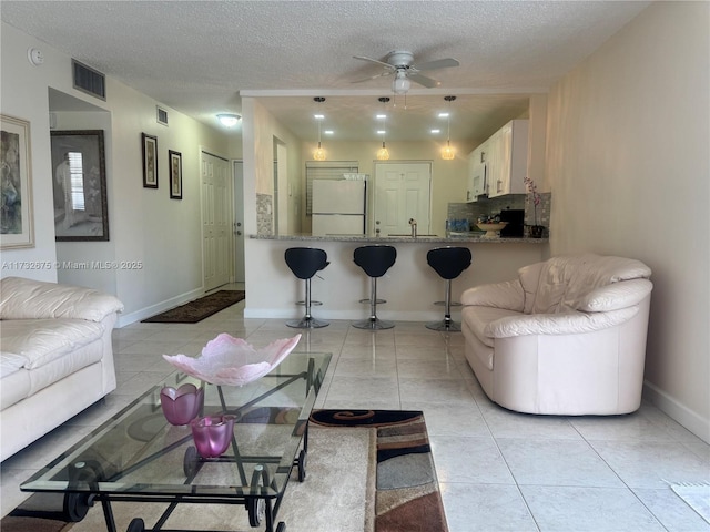 living room featuring ceiling fan, sink, a textured ceiling, and light tile patterned floors