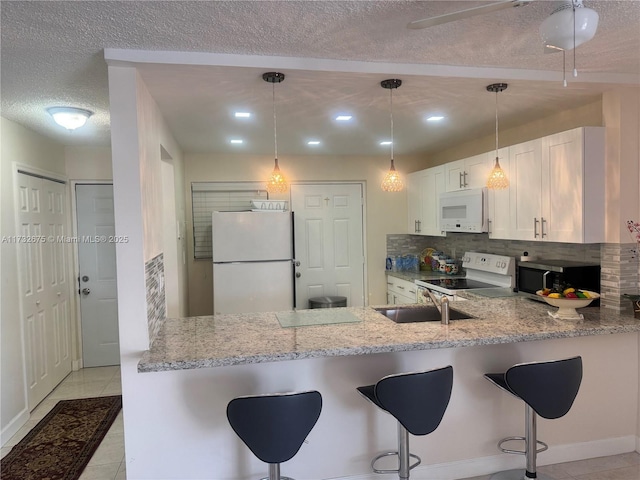 kitchen featuring white cabinetry, white appliances, light stone counters, kitchen peninsula, and a textured ceiling