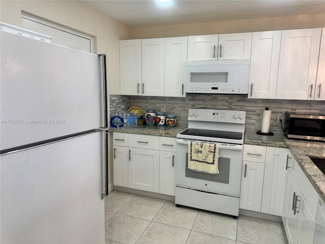 kitchen with tasteful backsplash, stone countertops, white cabinets, and white appliances