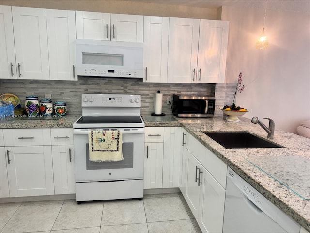 kitchen with light tile patterned flooring, sink, white cabinets, and white appliances