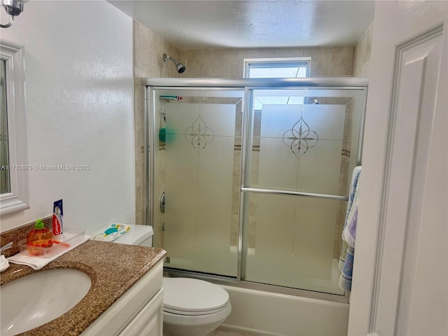 full bathroom featuring vanity, bath / shower combo with glass door, and toilet