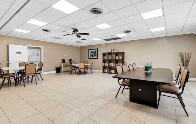 dining room with ceiling fan, light tile patterned floors, and a drop ceiling