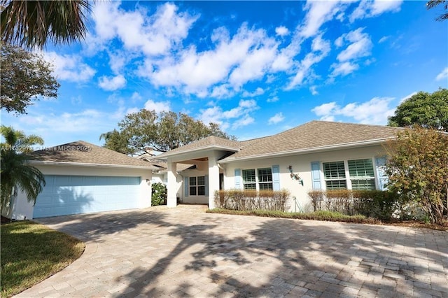 ranch-style house featuring a garage, decorative driveway, and stucco siding