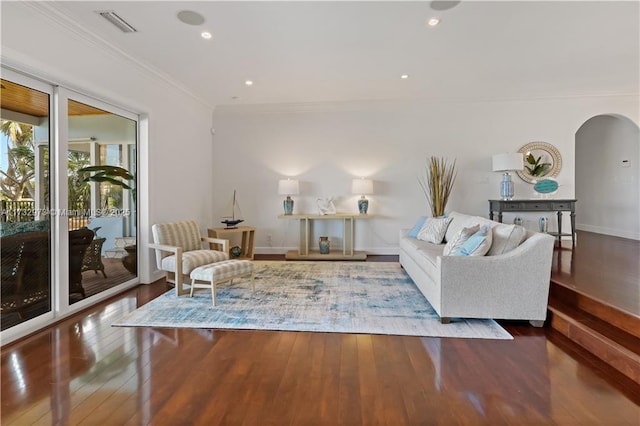 living room featuring arched walkways, recessed lighting, wood finished floors, baseboards, and crown molding