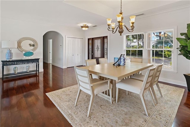 dining area featuring arched walkways, wood-type flooring, crown molding, and baseboards