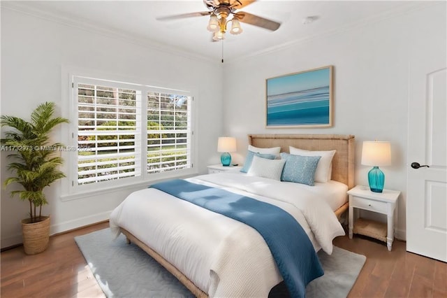 bedroom featuring a ceiling fan, crown molding, baseboards, and wood finished floors