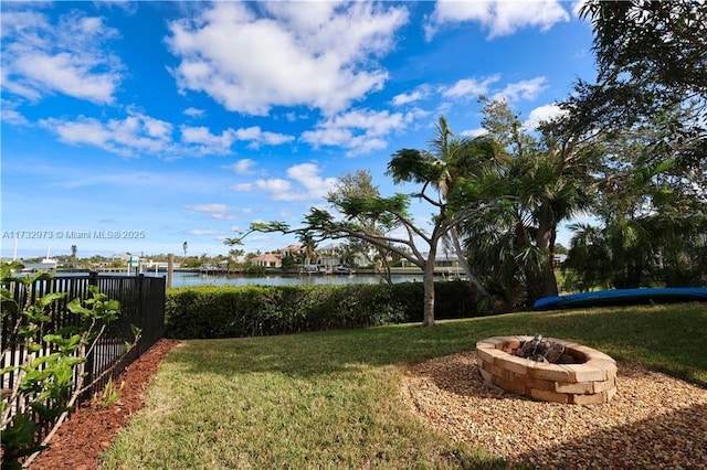 view of yard with an outdoor fire pit, a water view, and fence