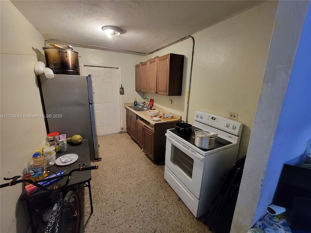 kitchen featuring sink, stainless steel fridge, a textured ceiling, and white electric range oven