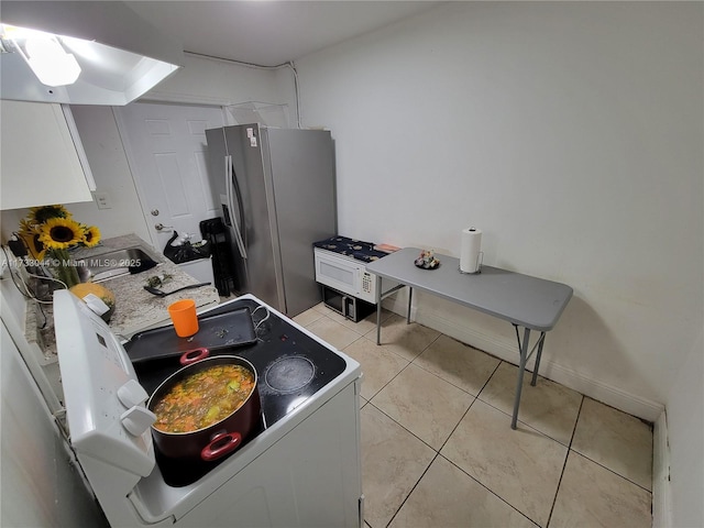 kitchen featuring white cabinetry, stainless steel fridge with ice dispenser, light tile patterned floors, and washer / dryer