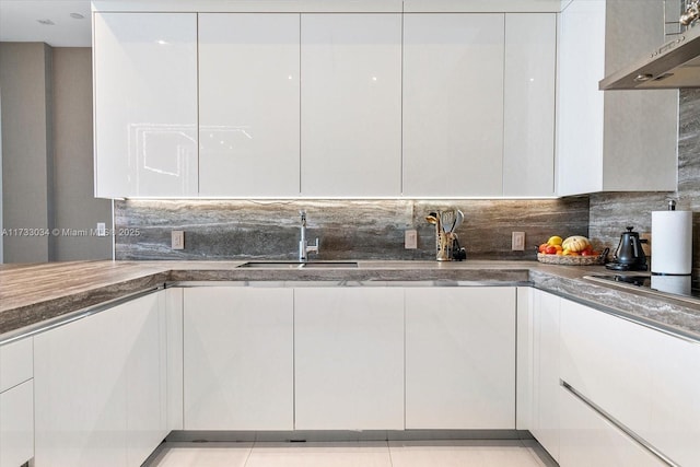 kitchen featuring sink, decorative backsplash, ventilation hood, and white cabinets