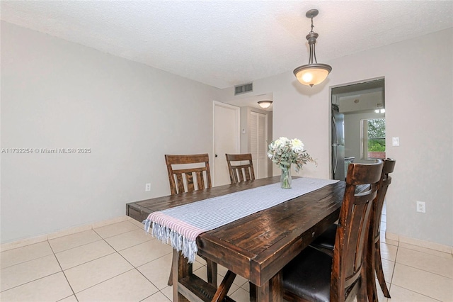 dining area featuring light tile patterned flooring and a textured ceiling